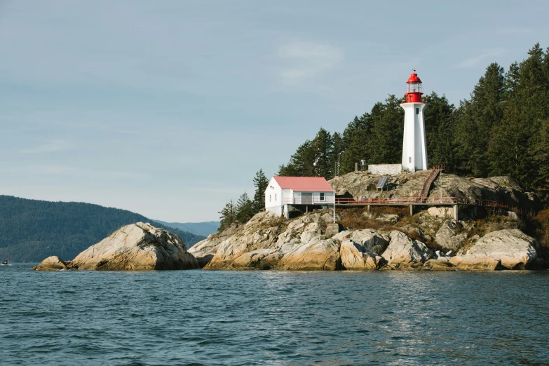 a red and white lighthouse is on the side of some rocks