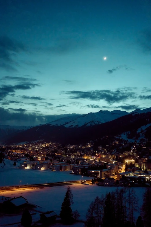 a snowy landscape with the city lights lit up