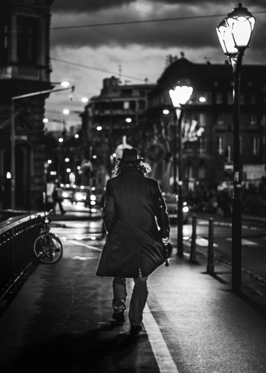 the silhouette of a person walking down a city sidewalk at night