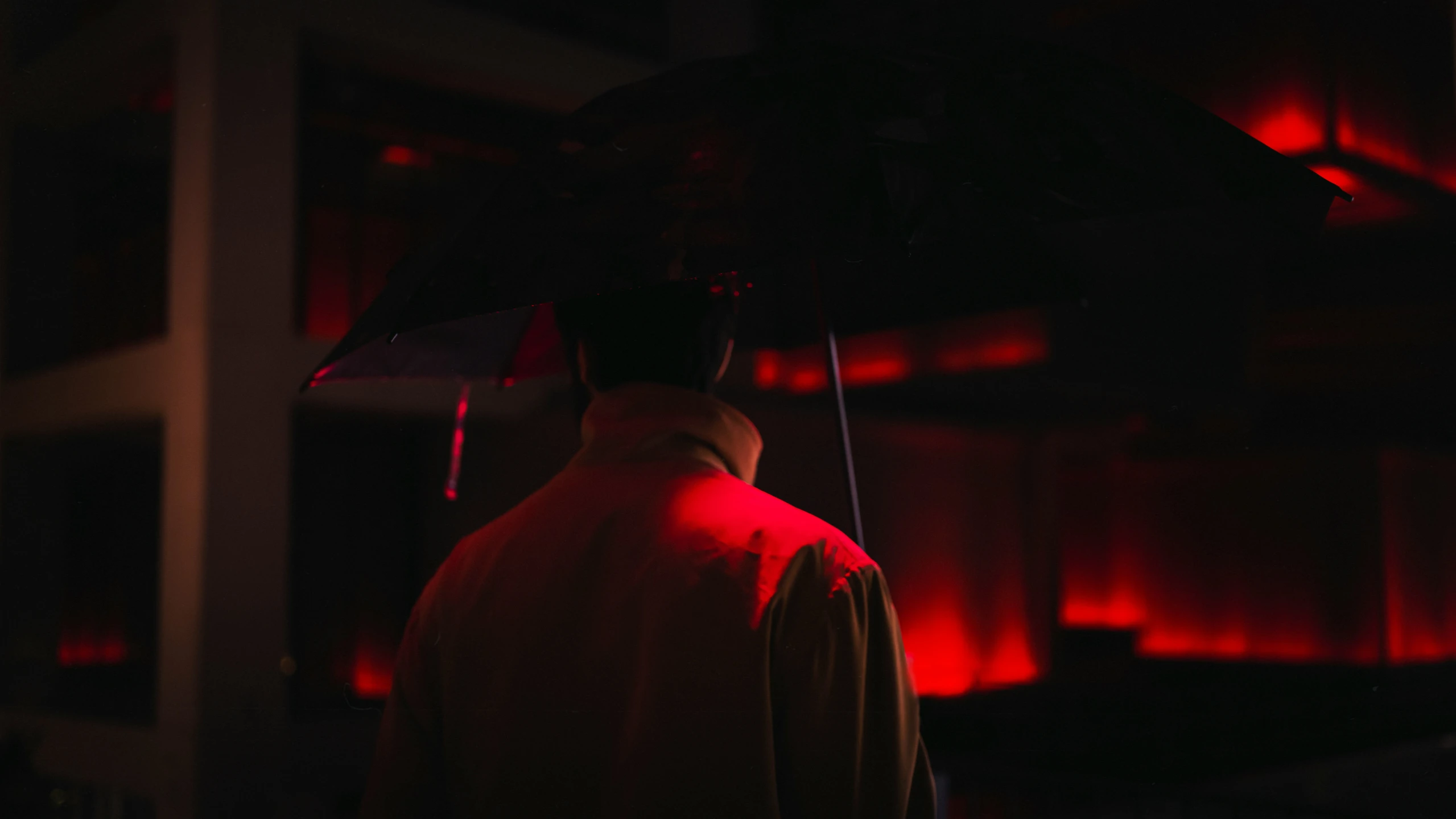 man in dark room, under umbrella at night