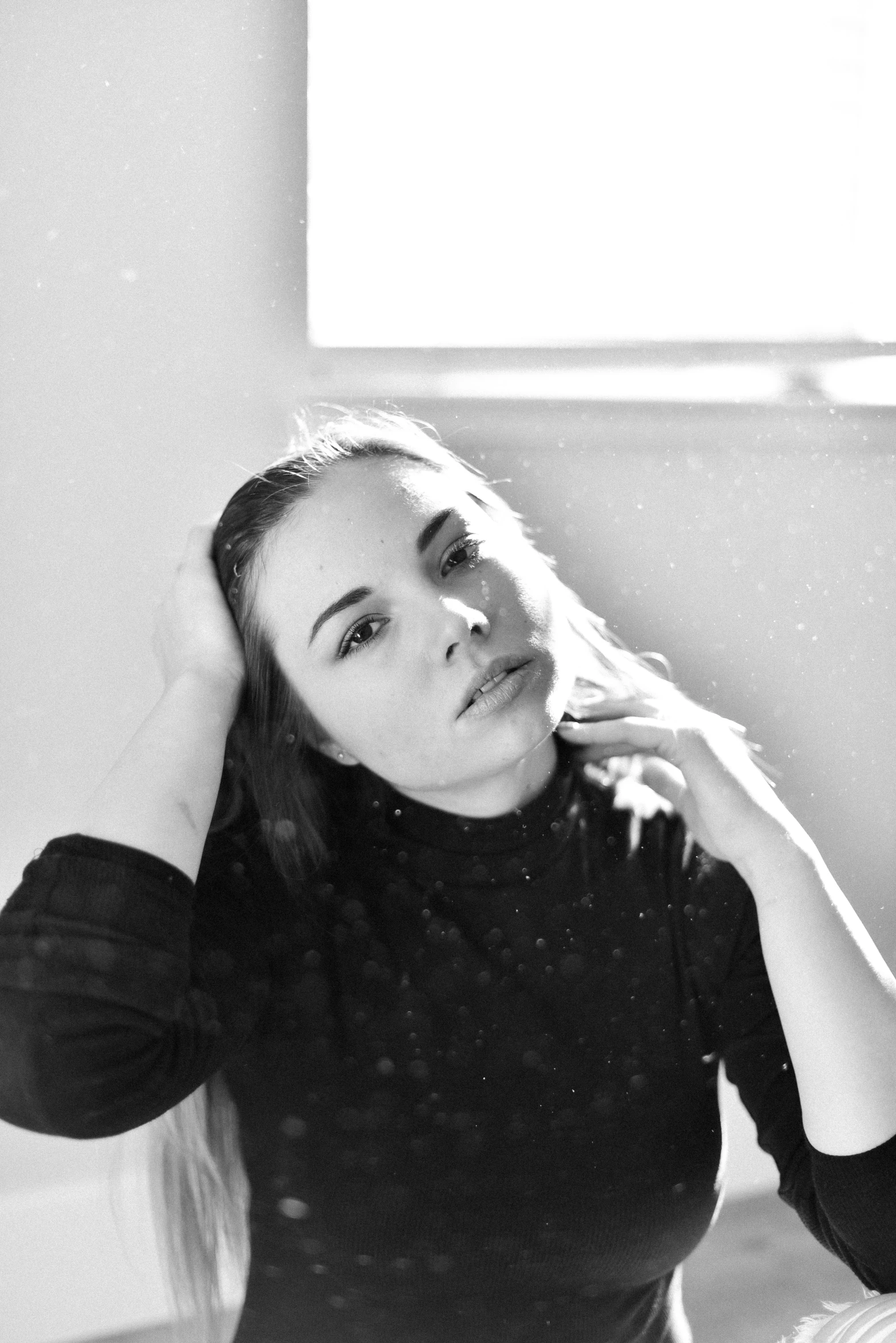 black and white po of a woman holding her hair in the wind