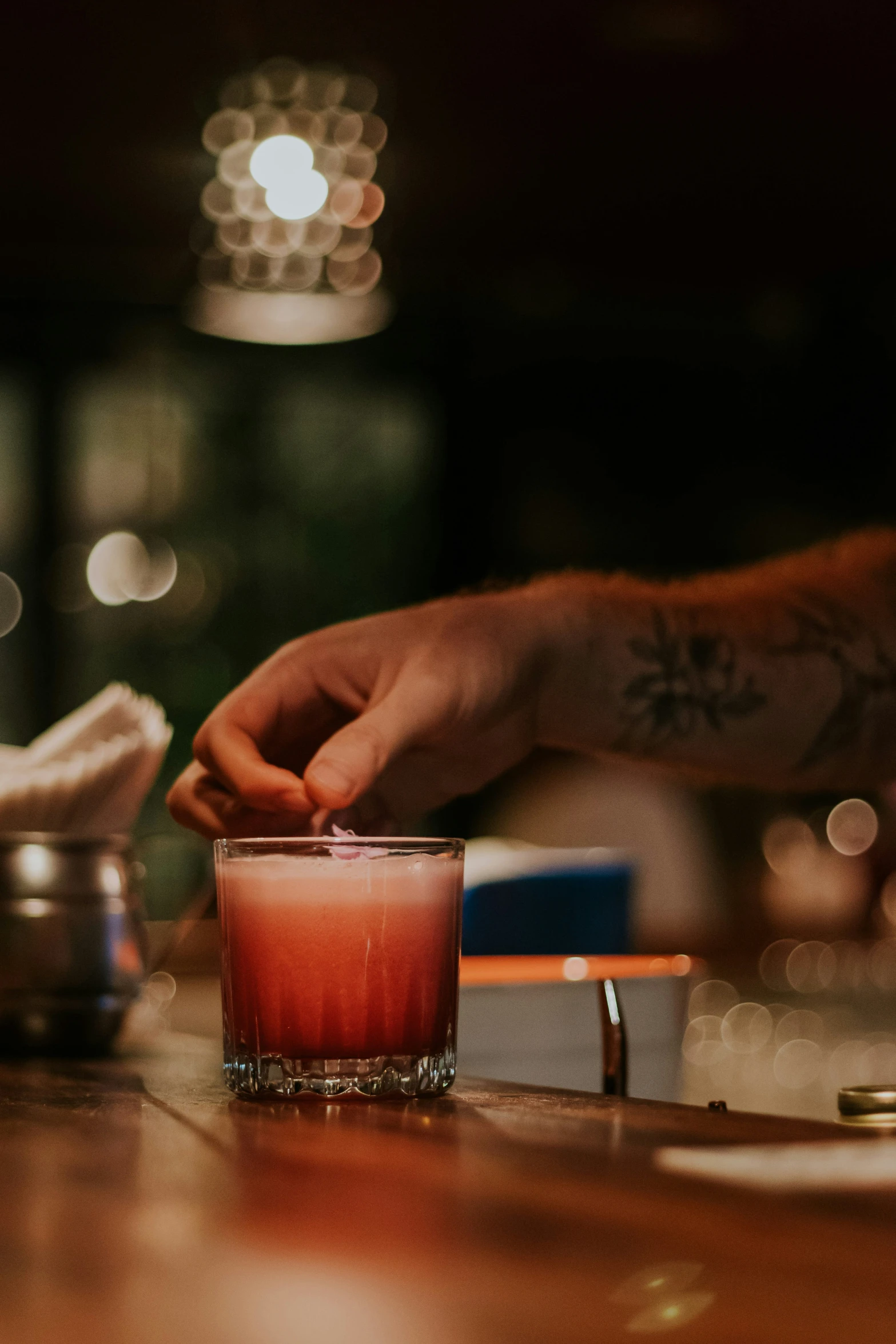 a hand placing a piece of red food on the top of a glass