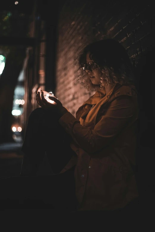 person in yellow coat holding up a lit cell phone