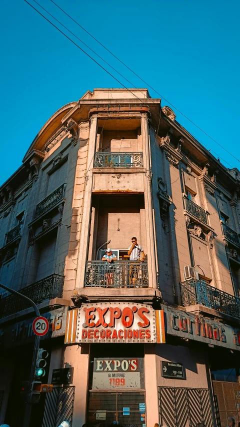 the front of an old building that has people standing on a balcony