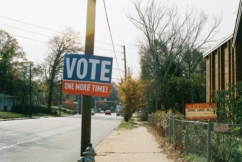 an election sign sits on a street corner