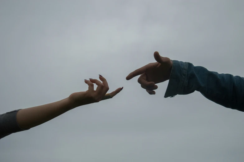 two people pointing at each other with their hands