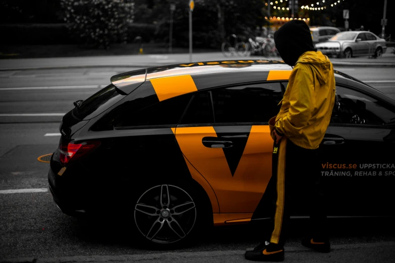 a person standing near a black and yellow car