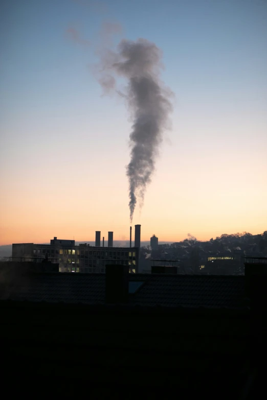 smoke coming out of chimneys and buildings at dusk