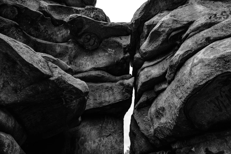 black and white pograph of a stone formation, the formation of rock formations and a cliff, with a man in the distance, on a sunny day trip