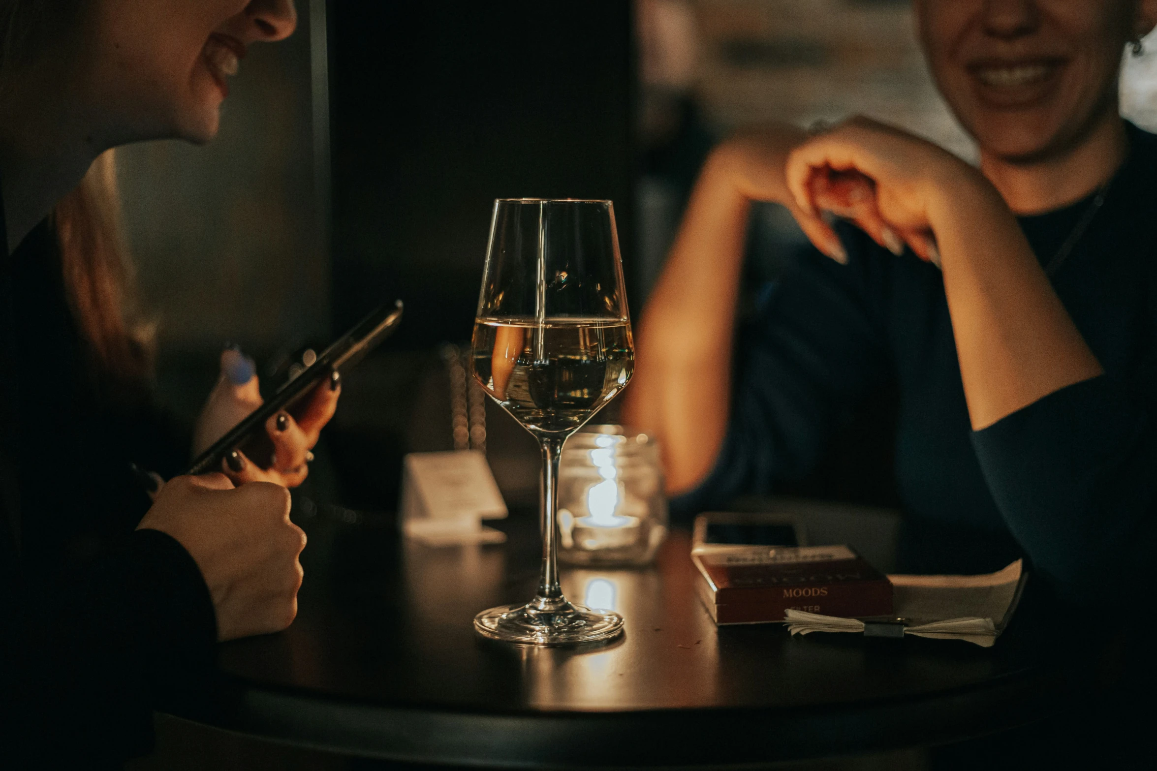 two people sitting at a table with glasses of wine