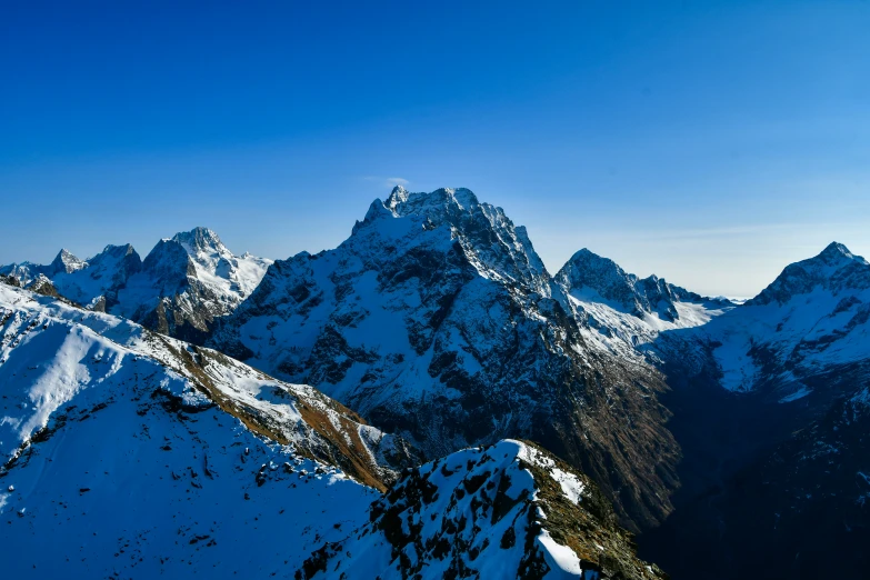 the view looking down on snowy mountains in the blue sky