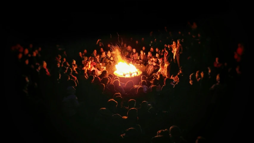 a group of people sitting around an outside fire