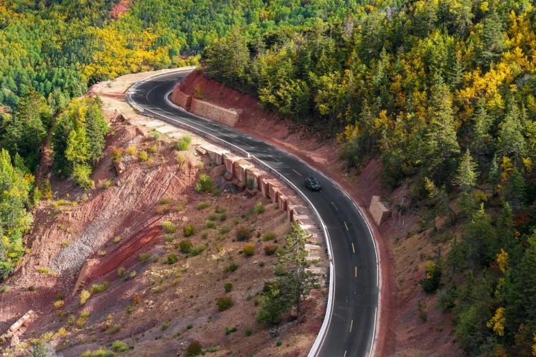 an aerial s of a winding road next to forest