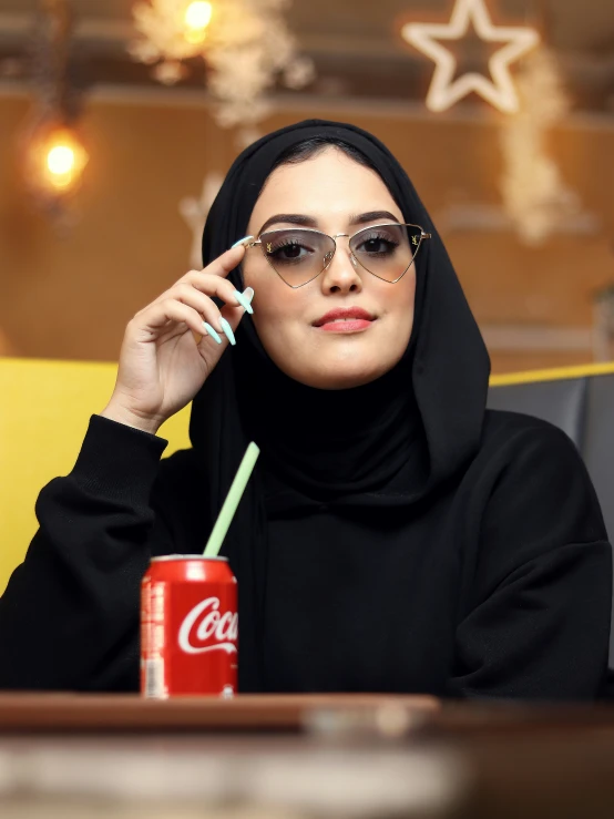 a young woman wearing a hijab sits at a desk