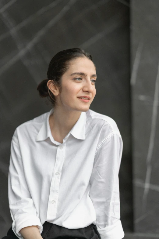 a woman in white shirt sitting on chair with her hands on her hips