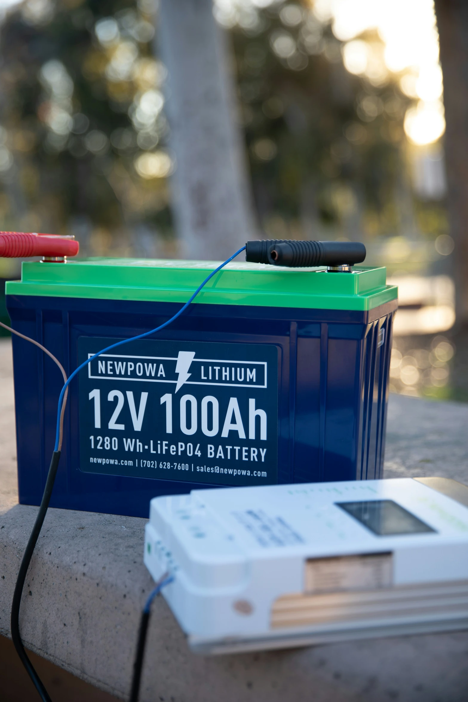 an emergency charger with some batteries and a blue box sitting on a ledge