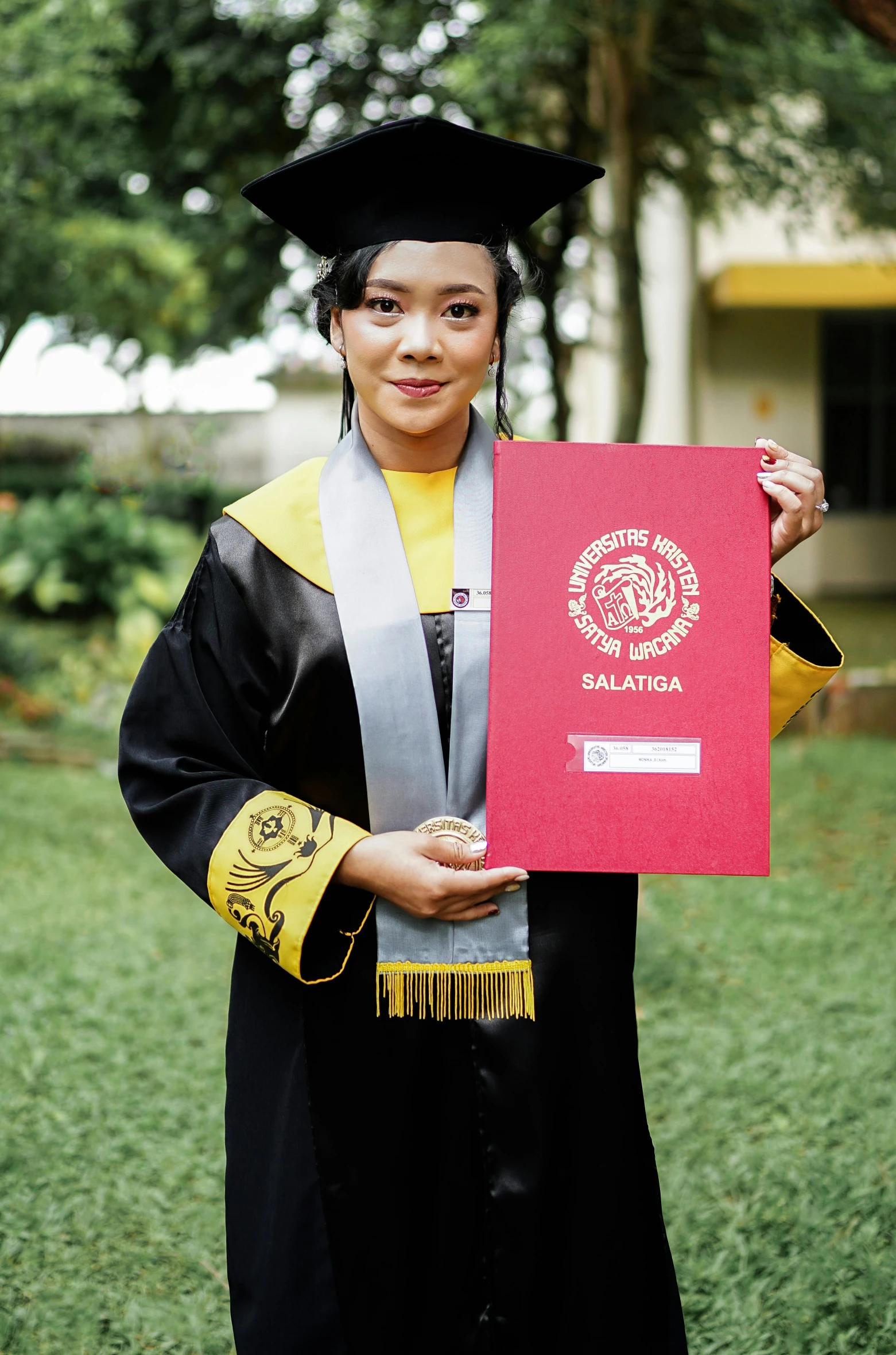 a woman in a cap and gown holding a certificate