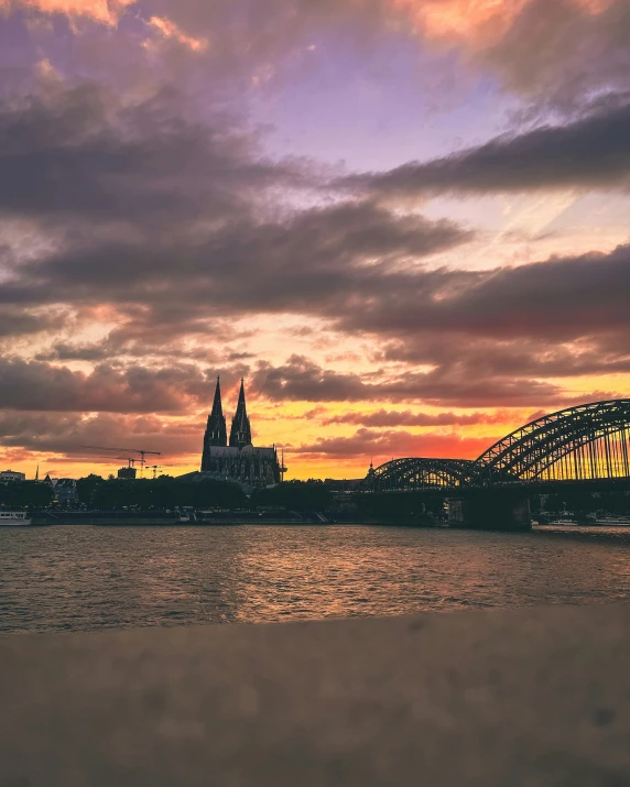 the sun sets on a bridge over the water