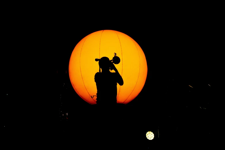 a silhouette of a man and a cat in front of an orange ball
