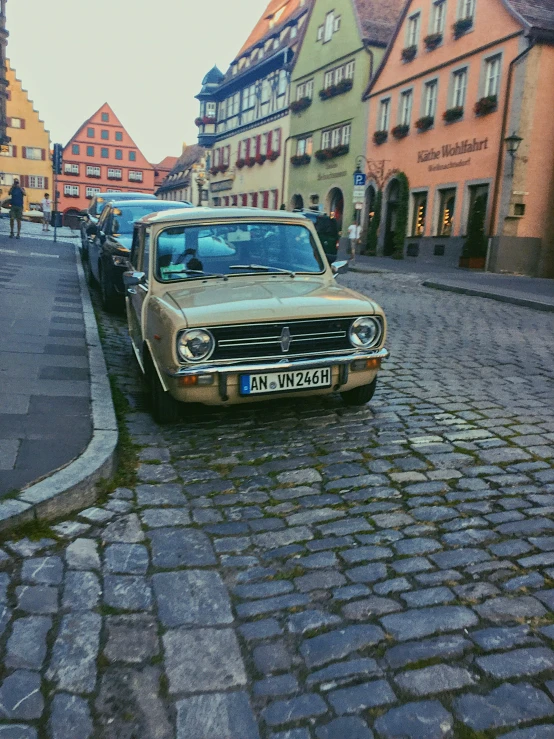 a tan and black car parked on the sidewalk