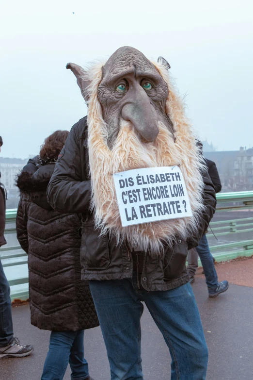 a man is wearing an animal mask and carrying a sign