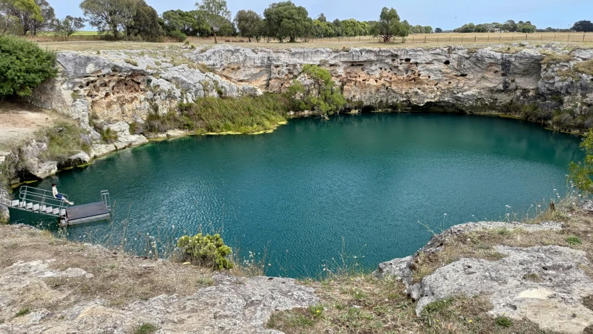 a beautiful blue pond surrounded by trees in an open area