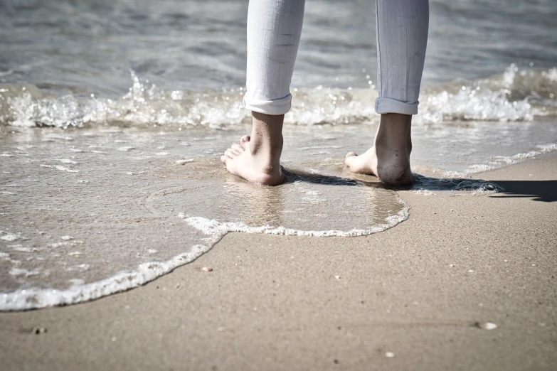 a woman standing on the sand near the water