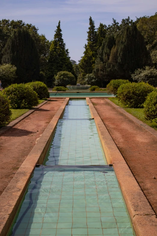 a long water feature sits in the center of an expanse of stone