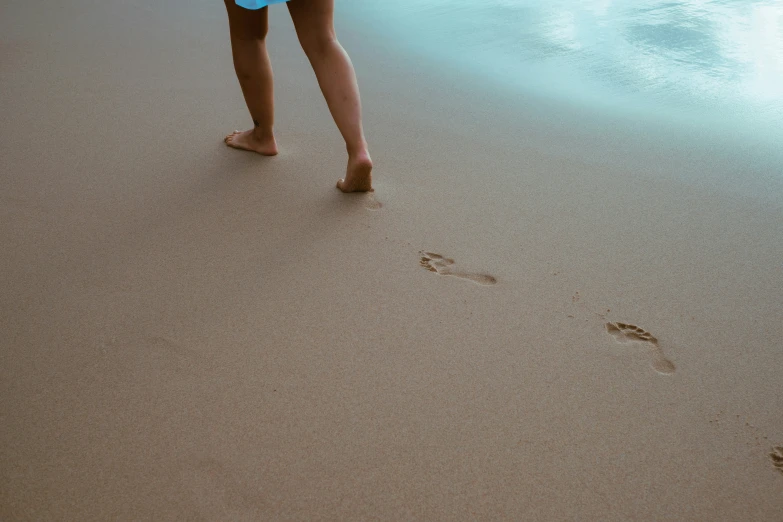 a person is walking on the beach near water