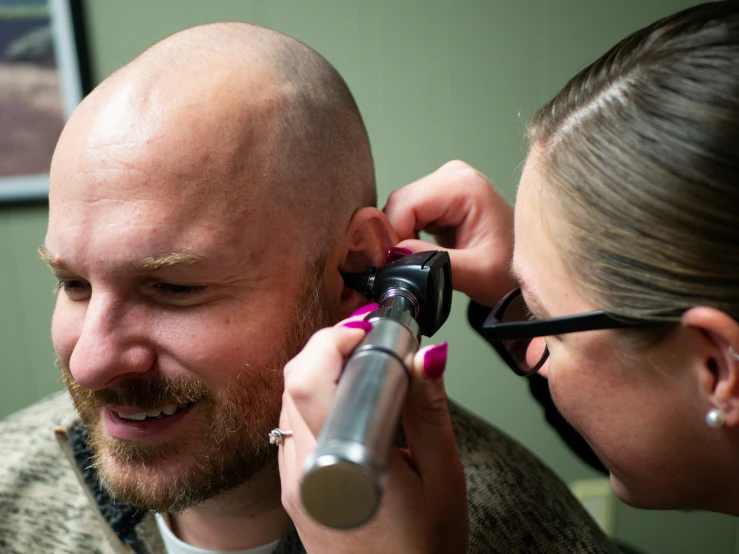 a man in glasses is getting his hair cut