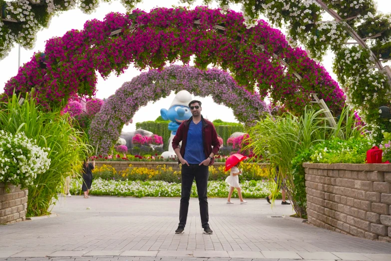 a man poses beneath a bunch of flowers and balloons