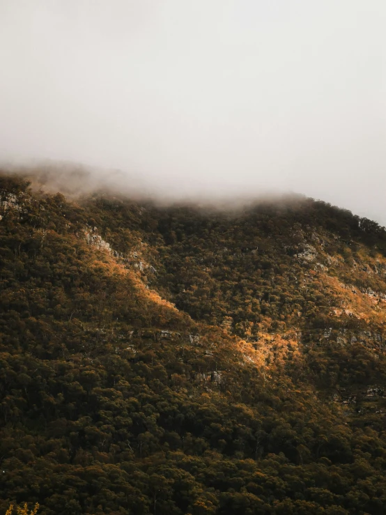 a distant, tall mountain side is covered in thick clouds