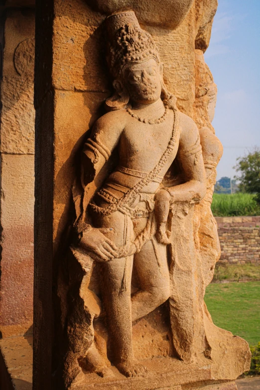 a statue stands behind a pillar on a brick