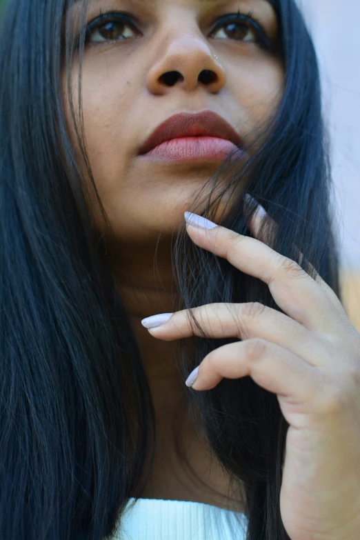 an asian woman poses with her hand on her face