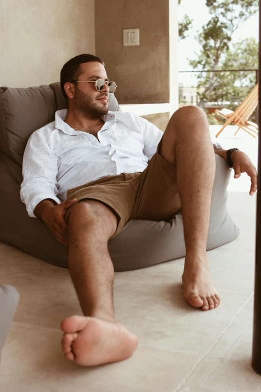 a man laying on top of a gray bean bag chair