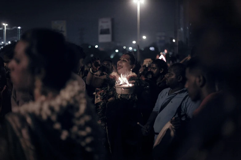 a woman is holding candles in the crowd