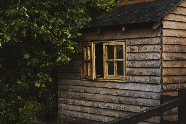 a wooden shed has three windows and an iron railing