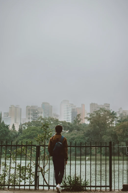 the person stands by the fence near the water