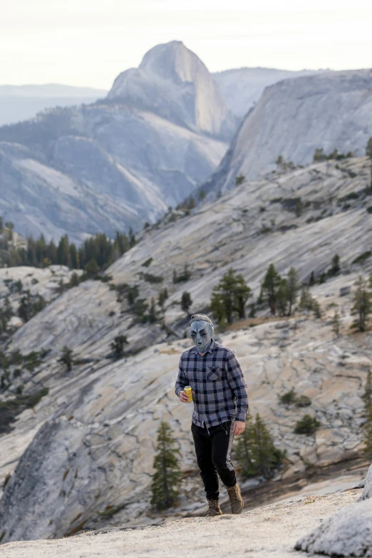 a man with a goat mask walking on a hillside