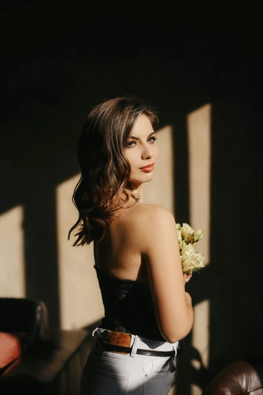 a woman standing in front of a window holding flowers