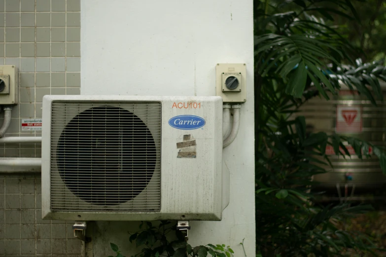 a air conditioner on the side of a building near plants