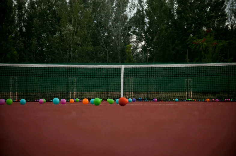 a tennis court with several balls on it and a net