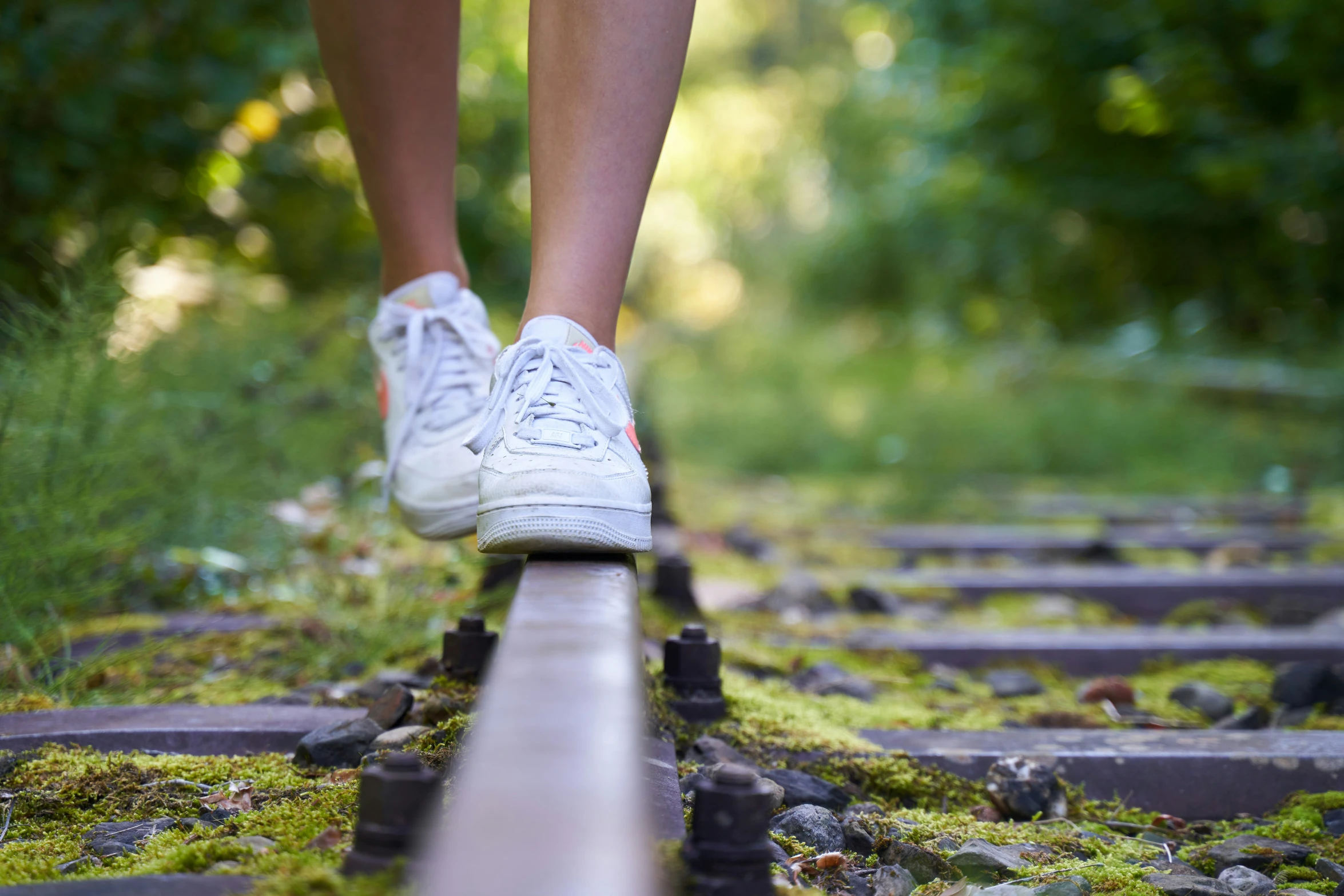 a young person walks on a railway tracks