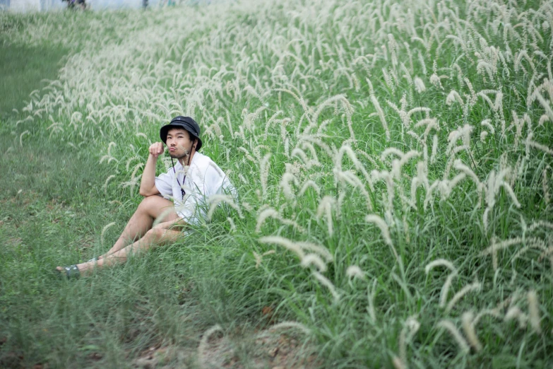 a person sitting in a grass field with one hand on her chest