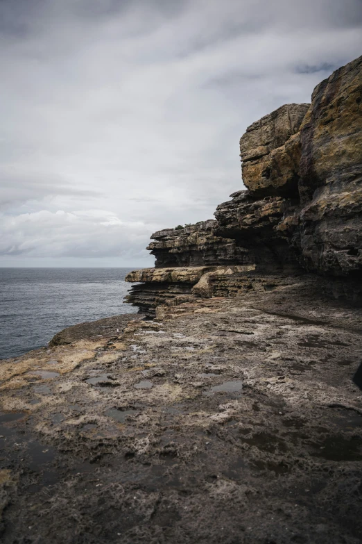 the rocky shore has several thin pools and small waves coming in