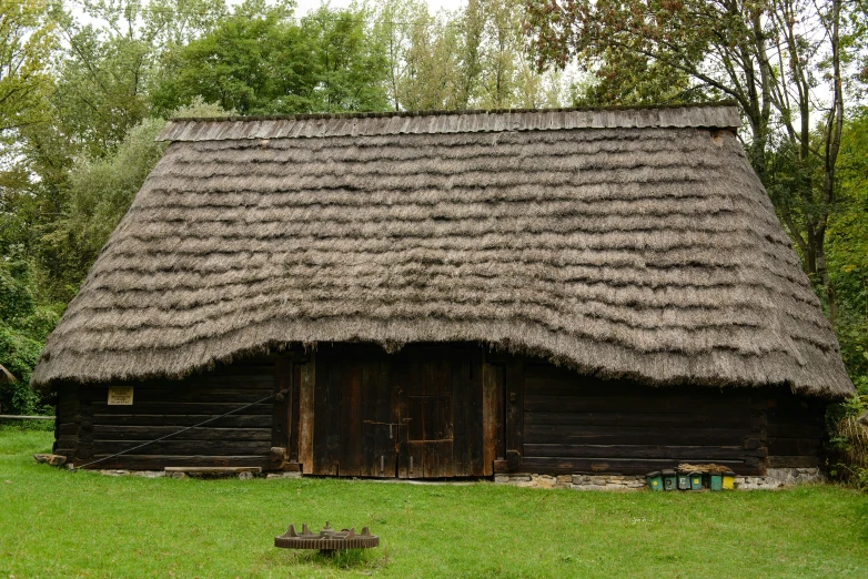 an old log cabin with a grass roof