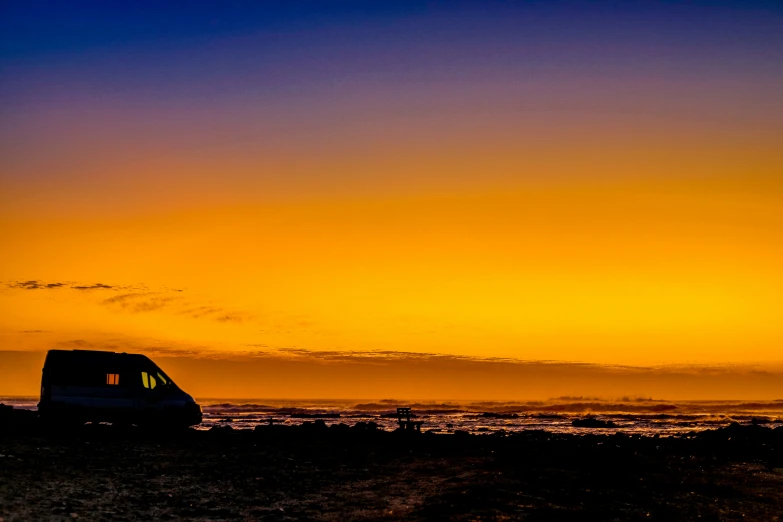 a small van on a beach next to the ocean