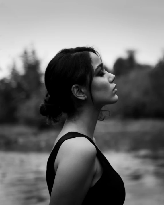 a woman standing in front of water on a cloudy day