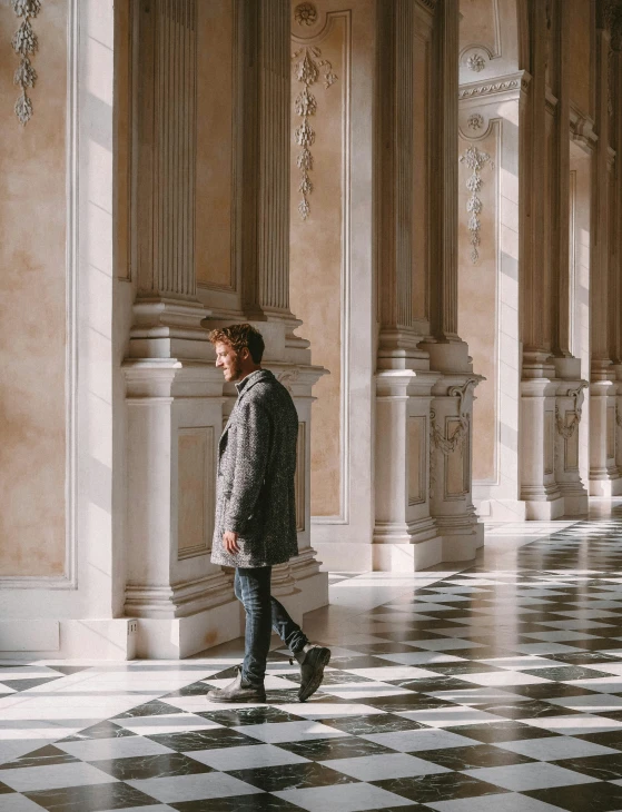 a man walks along a marble floor with columns
