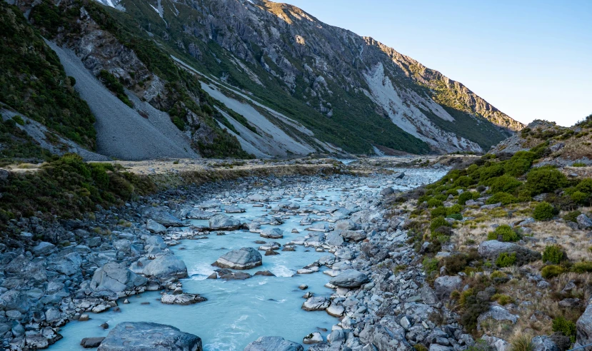 the sun shines brightly on some mountains next to a river